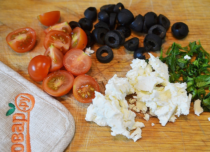 1. Этап. Сырный хлеб с маслинами и помидорами черри: Петрушку мелко порубите, черри порежьте пополам, маслины кружками. Козий сыр разомните вилкой. Постепенно все вмешайте в тесто.