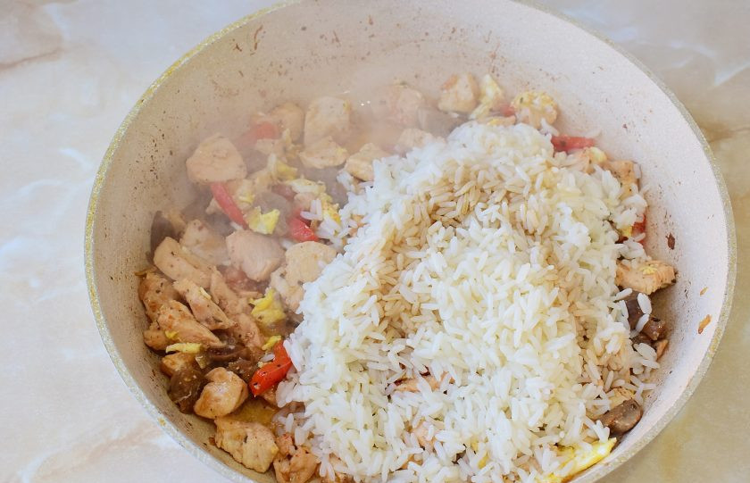 1. Этап. Тепаньяки с курицей: Выложите рис в сковороду. Добавьте соевый соус и кунжутное масло. Все перемешайте.