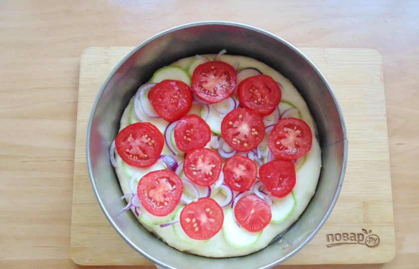 1. Этап. Испанская пицца: Красный лук очистите и нарежьте полукольцами. Помидоры также нарежьте кружками. Выложите эти овощи на тесто. При желании посыпьте слегка молотой паприкой.