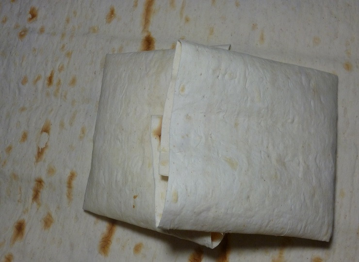 1. Этап. Быстрые пирожки из лаваша: 3. Аккуратно заверните края, затем сверните лаваш, сформировав конвертик, чтобы начинка не выпала во время обжаривания.