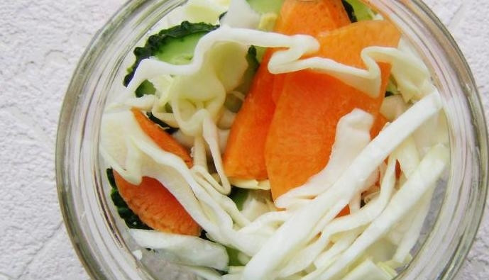 1. Этап. Салат из капусты и огурцов на зиму: Салат переложите в стерилизованные банки. Залейте его крутым кипятком так, чтобы тот покрыл все ингредиенты.