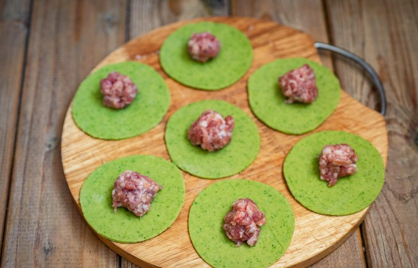 1. Этап. Зелёные пельмени со шпинатом: В центр каждого круга из теста положите по одной чайной ложке мясной начинки.