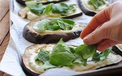 1. Этап. Инвольтини из баклажанов: 3. Баклажан нарежьте вдоль на тонкие пластины. Если баклажан большой, у вас должно получиться 8 пластин. На тарелку выкладывайте по две полоски и ставьте в микроволновку минуты на 3-4, чтобы пластины стали мягкими. Так проделайте со всеми пластинами. Промокните баклажановые пластины салфеткой, чтобы убрать лишний сок. На каждую полоску выложите сырную начинку. Шпинат порвите на кусочки и положите сверху на начинку.