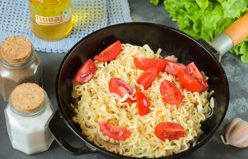 1. Этап. Острая корейская лапша: Промойте и нарежьте помидоры черри на четвертинки. Добавьте вместе с лапшой в сковороду.