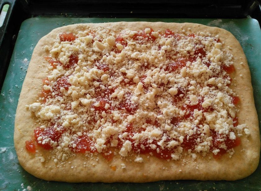 1. Этап. Тыквенный пирог с ягодами и штрейзелем: Смажьте основу густым джемом или яблочным повидлом, посыпьте частью приготовленного ранее штрейзеля.