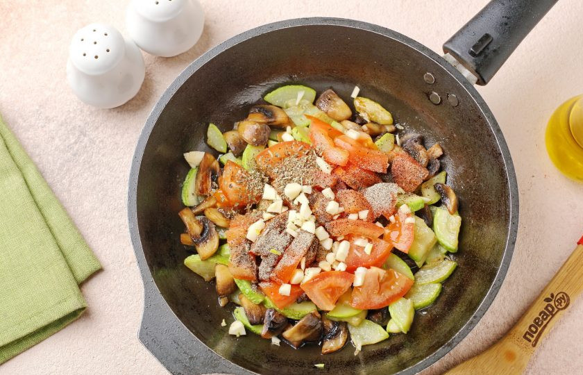 1. Этап. Паста с цукини и грибами: Добавьте нарезанный помидор, измельчённый чеснок, соль и специи по вкусу. Готовьте периодически помешивая еще около 3 минут.