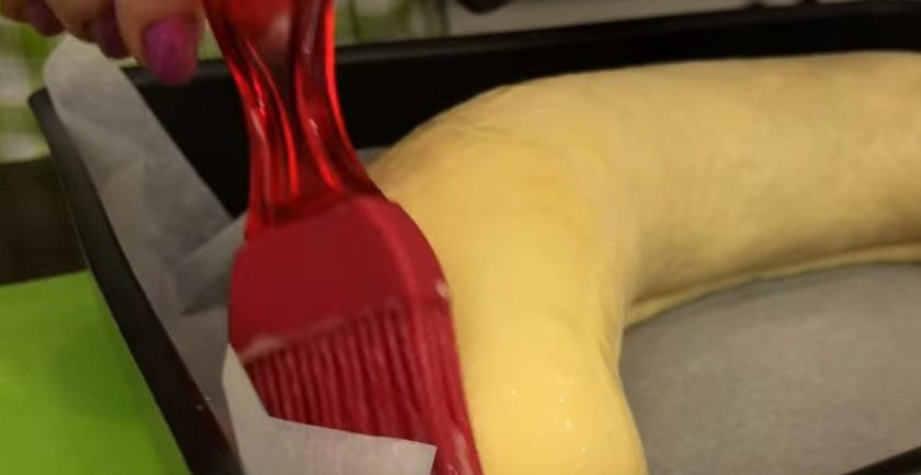 1. Этап. Рулет с черносливом и орехами в медовой корочке: 7. Смажьте рулет оставшимся желтком, взболтанным со столовой ложкой молока. Духовку разогрейте до 140 градусов, откройте дверцу и поставьте на нее противень с рулетом.