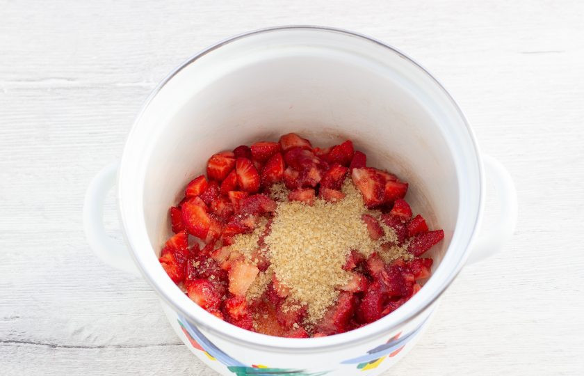 1. Этап. Сырные клецки с клубничным соусом: В небольшую кастрюлю выложите клубнику, засыпьте её тростниковым сахаром. Поставьте на плиту.