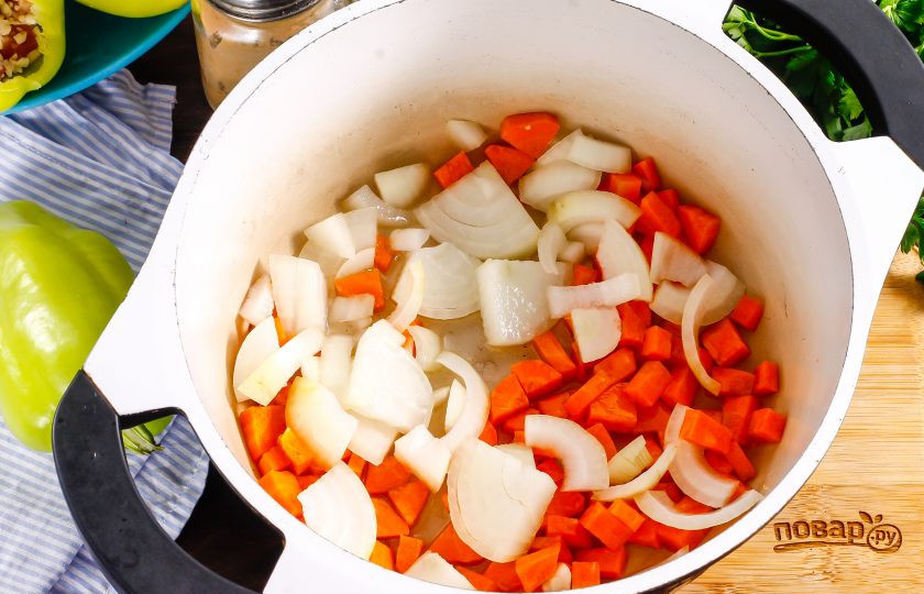 1. Этап. Фаршированный перец по-узбекски: Очистите от кожуры лук и морковь, нарежьте крупными кубиками, предварительно промыв. Прогрейте в казане растительное масло и обжарьте в нем овощные нарезки примерно 3-5 минут до мягкости.