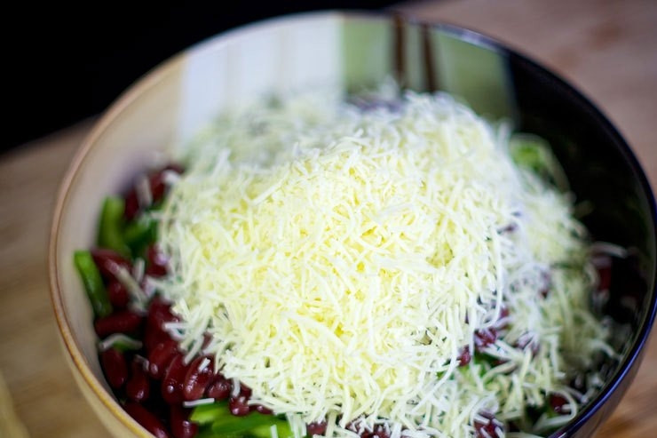 1. Этап. Cалат с крабовыми палочками и фасолью: Натрите сыр. Высыпьте в салатницу.