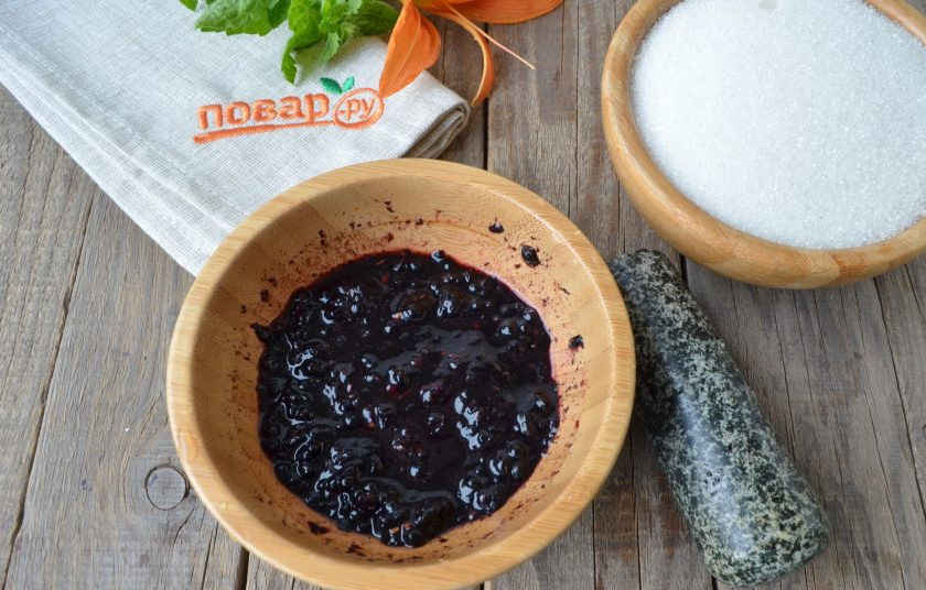 1. Этап. Варенье из ежевики без варки: Возьмите ступку или просто удобную глубокую посудину и тяжелый пестик. Не большими порциями насыпайте ягоды и давите, растирайте пестиком, чтобы образовалась кашица. Добавьте сахар, перемешайте и оставьте на 2-2,5 часа варенье. За это время нужно несколько раз его перемешать, чтобы полностью растворить сахар.