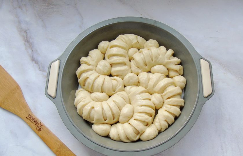 1. Этап. Отрывной пирог из дрожжевого теста с творожной начинкой: У вас получится 6 рогаликов. Из последнего седьмого шарика теста скатайте 12 маленьких шариков. Выложите рогалики и шарики в форму для выпечки, как показано на фото.