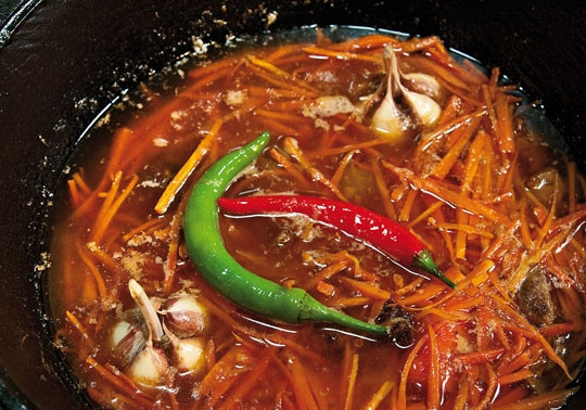 1. Этап. Байрам-плов: Добавьте в казан нарезанную соломкой морковь, тут же тщательно перемешайте её с остальными компонентами. Обжаривайте, пока морковь не обмякнет.