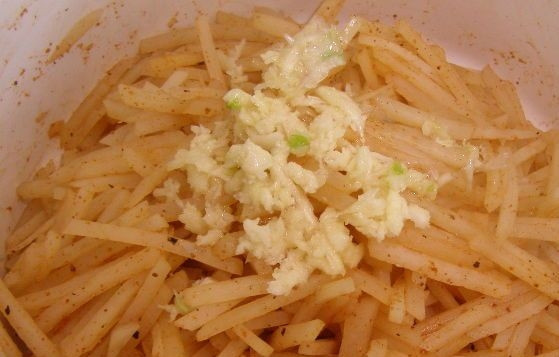 1. Этап. Салат картофельный корейский: Уложите салат горкой. Сверху положите чеснок и налейте горячее масло. Добавьте соевый соус, перемешайте.