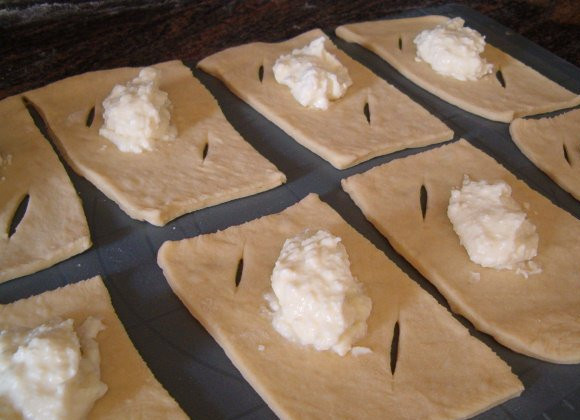 1. Этап. Плюшки с творогом: Пласт теста нарезаем на прямоугольники. На краях делаем надрезы. В середину выкладываем творог.