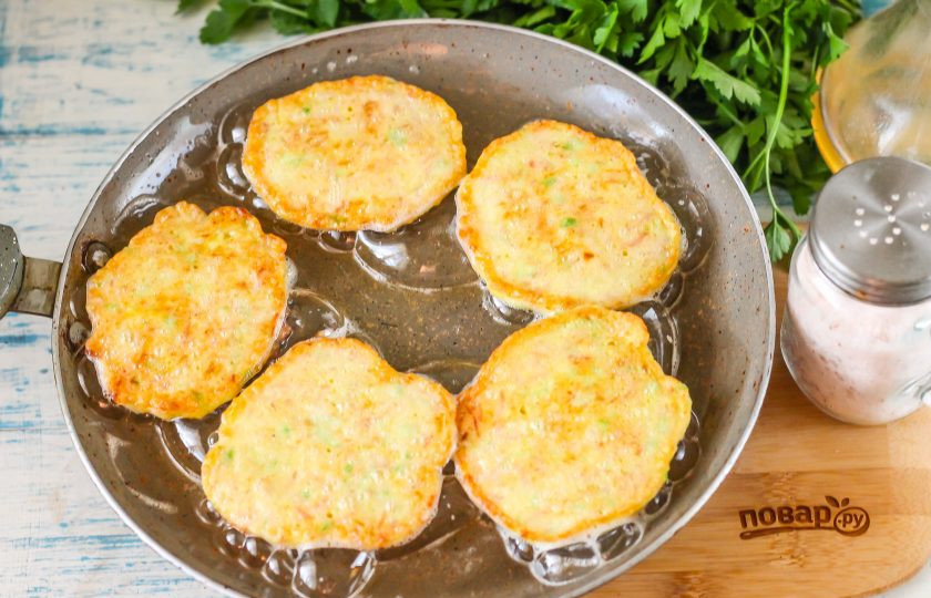 1. Этап. Кабачковые оладьи с колбасой: Прогрейте сковороду с растительным маслом. Столовой ложкой выложите в него кабачковой тесто и обжарьте оладьи с каждой стороны по минуте на умеренном нагреве до румяности.