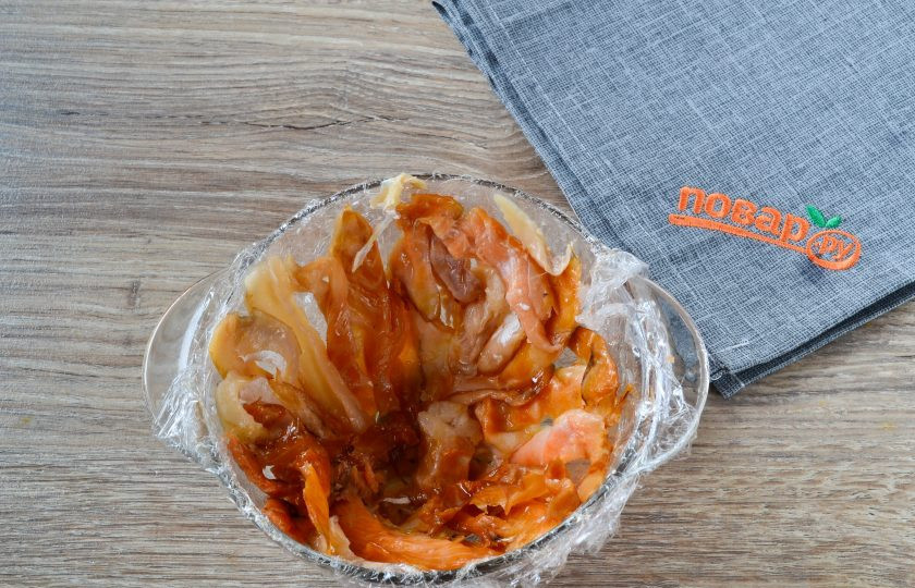 1. Этап. Закусочный торт с крабовой начинкой: Глубокий салатник застелите пищевой пленкой. Выложите по всей поверхности дна и стенок кусочки красной рыбы.