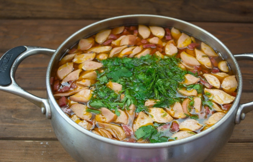 1. Этап. Солянка с сосисками: Добавьте специи, соль, измельченную зелень. Дайте закипеть и выключайте.