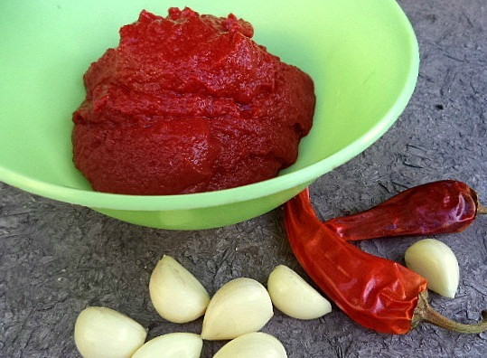 1. Этап. Аджика со сливами: Теперь подготовим остальные овощи. Помоем чили перчик, освободим его от стручков, а также от внутренних семян. Затем почистим чеснок. По желанию его можно заменить луком или хреном. Еще нам понадобится томатная паста. Подойдут, конечно же, и свежие помидоры. Можно делать сливы с томатами в любых пропорциях. Они подчеркивают друг друга.