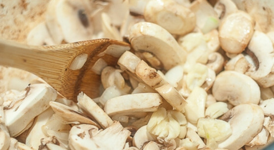 1. Этап. Мясо, тушенное с грибами: 4. Очистите грибы и нарежьте пластинками, выложите их в кастрюлю. Очистите лук и нарежьте его кубиками, измельчите чеснок, добавьте все к грибам.