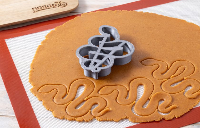 1. Этап. Имбирное печенье на Новый год Змеи: Раскатайте тесто в пласт на слегка присыпанной мукой поверхности до 3-4 мм.  Вырежьте печенье с помощью формочки змеи.