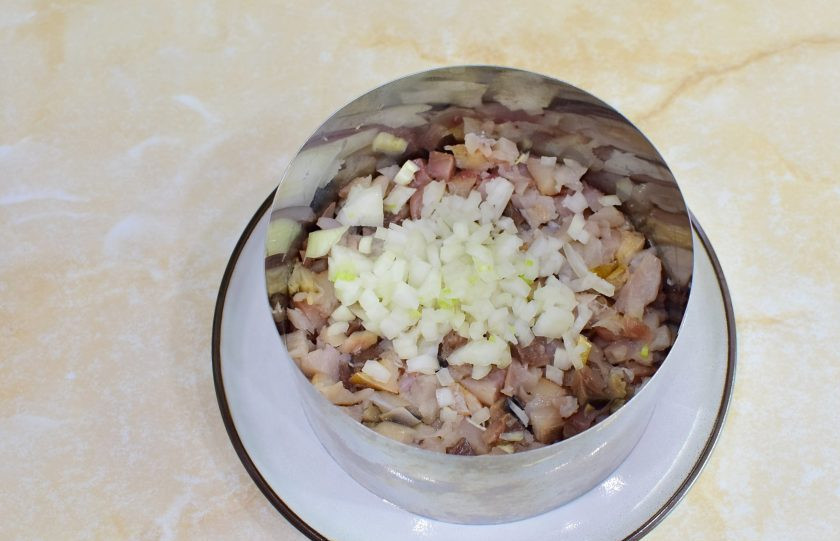 1. Этап. Салат Мимоза с копчёной скумбрией: Скумбрию очистите от костей и нарежьте на кусочки. Выложите следующим слоем салата. По рыбе выложите мелко нарезанный лук.