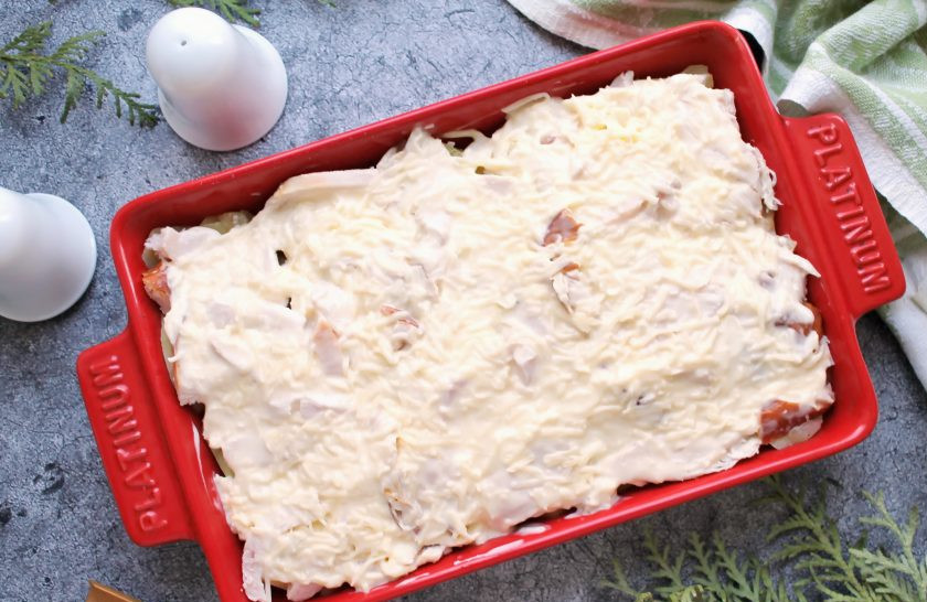 1. Этап. Картошка с копченой курицей в духовке: Сыр натрите на средней терке, добавьте майонез, воду и измельченный чеснок, перемешайте. Получившейся массой залейте верх картошки с копченой курицей.