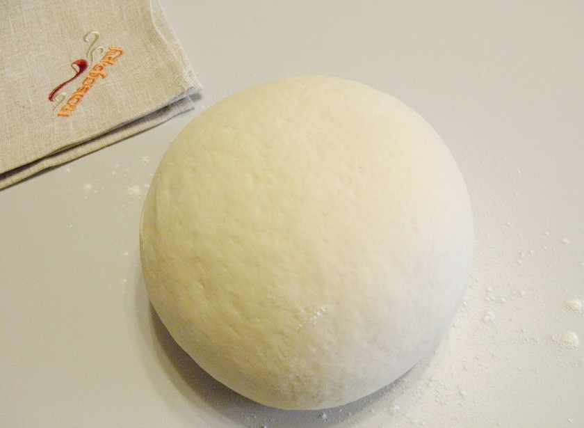 1. Этап. Постное тесто для вареников: Когда тесто будет достаточно плотным, перейдите на удобную рабочую поверхность. Притрусите ее мукой. Переложите тесто и месите до тех пор, пока оно не станет однородным, тугим, пластичным. Чтобы проверить готовность теста, сделайте надрез острым ножом, внутри тесто должно быть гладким.