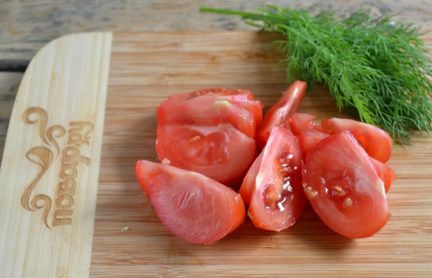 1. Этап. Маринованная капуста с помидорами: Каждый помидор разрежьте пополам, а затем половинки порежьте еще на 3-4 дольки.