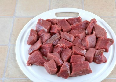 1. Этап. Тушеная говядина на сковороде: Говядину промываем проточной водой. Оставляем обсыхать на доске. Нарезаем острым ножом на равные кусочки, не очень мелко.