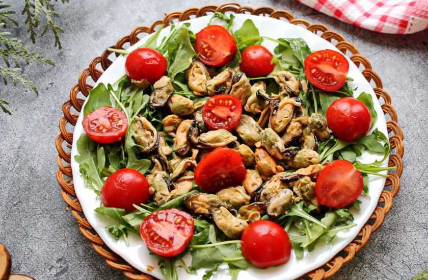 1. Этап. Салат с мидиями, моцареллой и рукколой: Черри разрежьте пополам и разложите поверх мидий и рукколы.