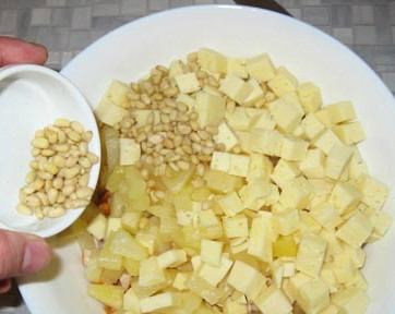 1. Этап. Салат с ананасом, курицей и сыром: Сыр выкладываем в общую массу с салатом. Берем немного кедровых орешков, высыпаем их в салат. Чем больше орешков, тем насыщенней получится наш салат.