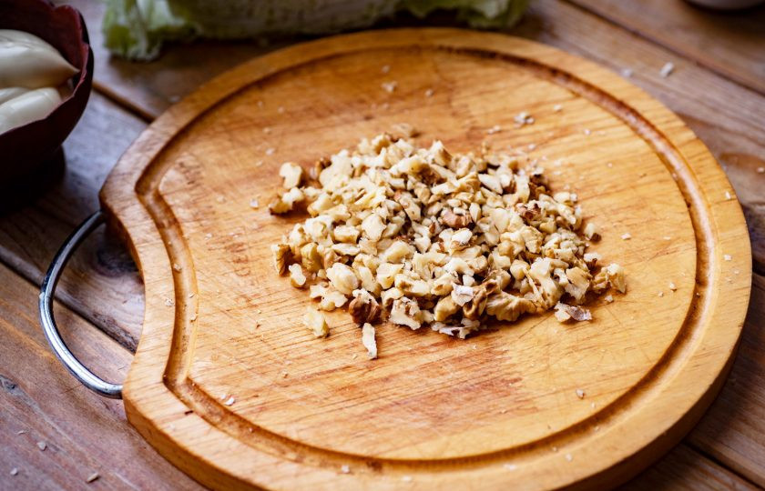 1. Этап. Салат с пекинской капустой, крабовыми палочками и сыром: Грецкие орехи мелко нарежьте ножом.