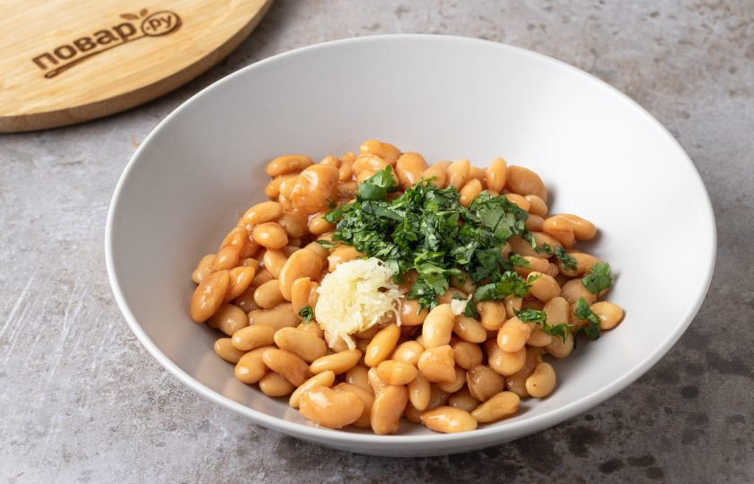 1. Этап. Салат с фасолью в томатном соусе: Чеснок пропустите через пресс, кинзу мелко порежьте. Добавьте к фасоли.