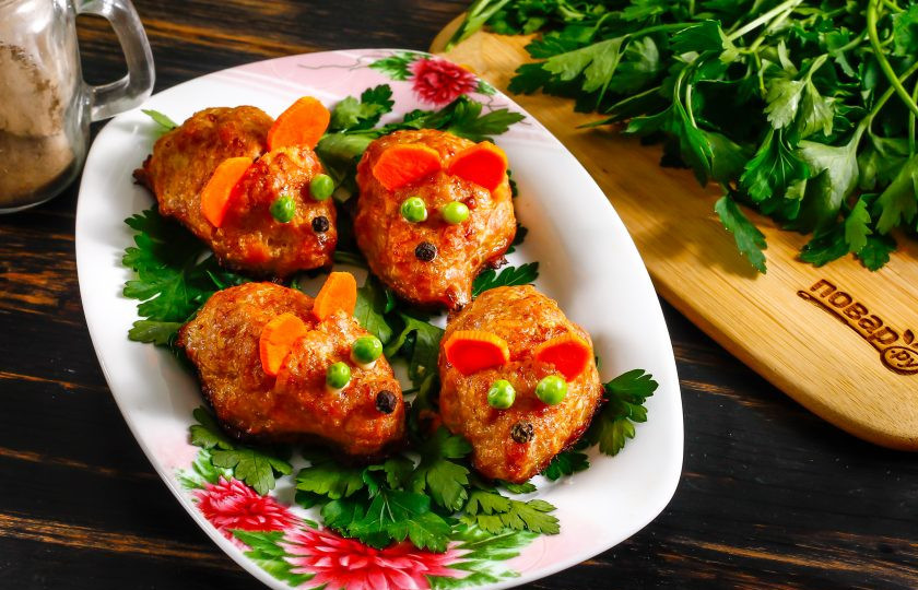 1. Этап. Котлеты Мышки: Выложите на тарелку свежую зелень. Очистите морковь от кожуры, промойте в воде и нарежьте кружочками. По желанию овощ можно предварительно отварить. Сделайте разрез в котлете и вставьте в него два кружочка моркови - ушки мышки. С помощью майонеза приклейте глазки из горошка и носик из черного перца. Если хотите, можете сделать хвостик из сыра, если нет - оставьте забавных хомячков.