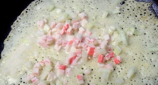 1. Этап. Блины с крабовым припеком: Раскалите на плите сковороду для блинов, смажьте ее растительным маслом. Затем вылейте на нее тесто, посыпьте крабовыми палочками с луком и слегка прижмите начинку лопаткой.