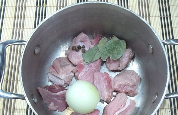 1. Этап. Классический суп Харчо: Свинину промойте, удалите жир, нарежьте мясо кусочками. Лук почистите. Добавьте эти ингредиенты в кастрюлю вместе с лавровым листом и перцем горошком.