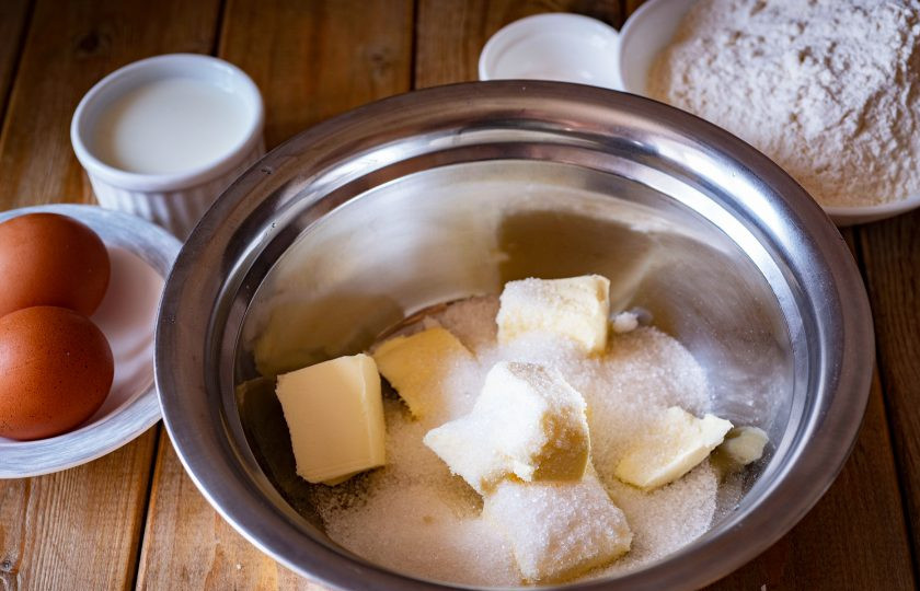 1. Этап. Яблочные кексы: В просторную миску выложите кусочки мягкого сливочного масла, добавьте сахар. Миксером взбивайте эти ингредиенты до получения кремообразной массы.