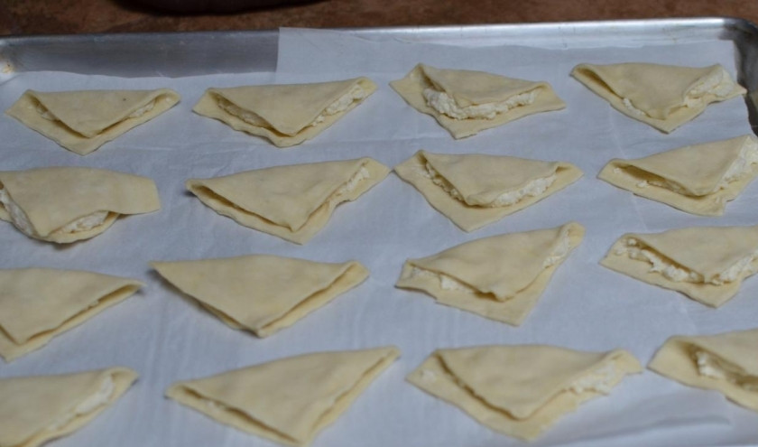 1. Этап. Слойки с творогом: Свернутые треугольники выложить на бумагу в противень для выпекания.