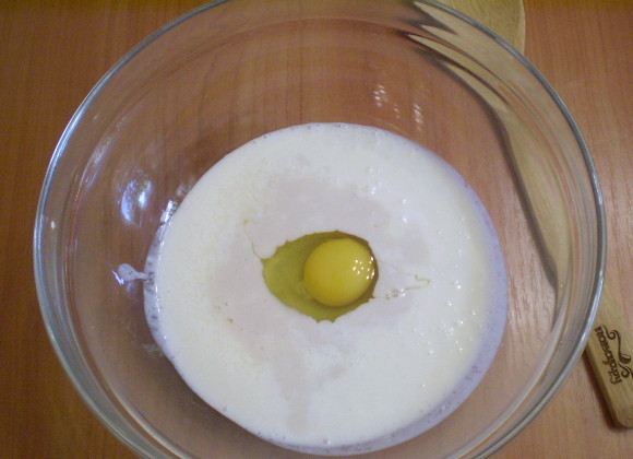 1. Этап. Дрожжевые оладьи на кефире: Добавляем яйцо, размешиваем.