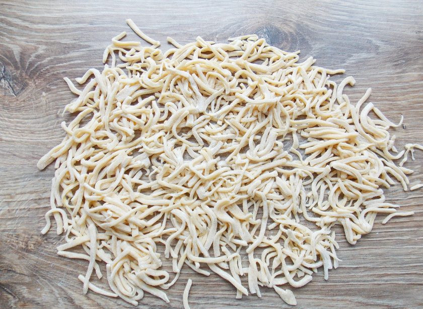 1. Этап. Домашняя лапша в хлебопечке: Извлеките тесто из холодильника, разделите его на несколько частей и каждую тонко раскатайте. Порежьте тесто на полоски, сложите стопочкой и нарежьте тонкую лапшу. Чтобы она не слипалась, пересыпьте ее мукой. Сушите такую лапшу при комнатной температуре, рассыпав в один слой, или в духовке на низкой температуре.