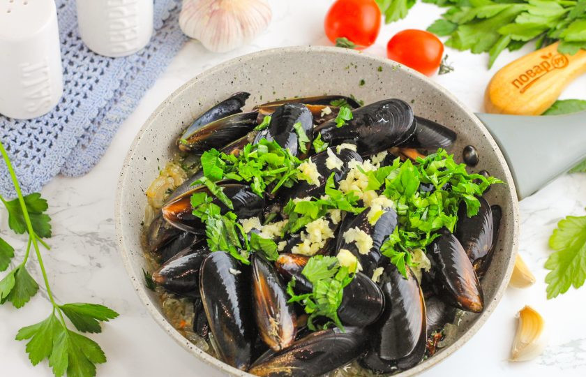 1. Этап. Мидии Мариньер: Измельчите промытую петрушку и спрессуйте чесночные зубчики. Добавьте все в емкость к мидиям, перемешайте. Томите мидии в соусе примерно 3-4 минуты под крышкой, время от времени перемешивая. Долго готовить морепродукты не нужно, они будут готовы максимум за 5 минут в зависимости от величины раковин.