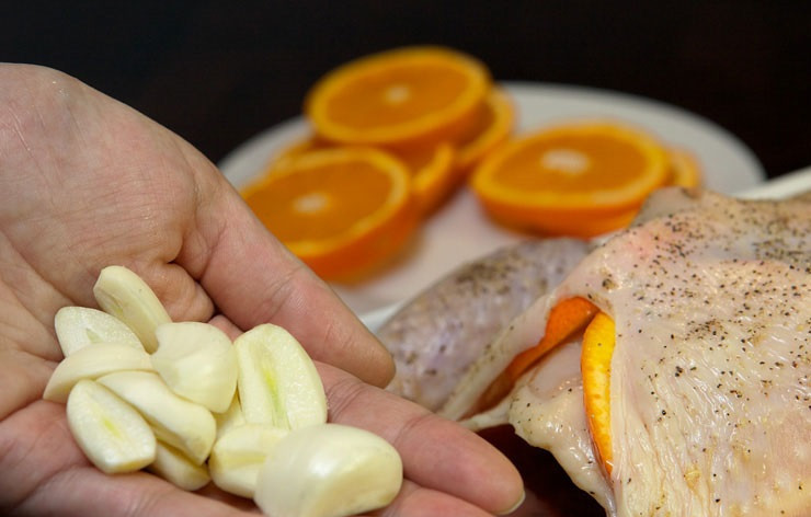 1. Этап. Курица под сладким соусом: 5. Очистите чеснок, нарежьте крупные зубчики на 2-3 части. Выложите под кожицу и внутрь тушки. Также вы можете использовать по рецепту приготовления курицы под сладким соусом немного измельченного имбиря.