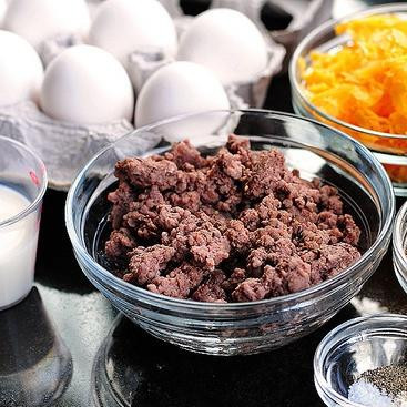 1. Этап. Фритата Чизбургер: 1. Разогреть духовку до 200 градусов. Смазать форму для выпечки или глубокую тарелку небольшим количеством масла или сбрызнуть маслом в спрее. Обжарить говядину в сковороде на среднем огне, приправив солью, перцем и чесночным порошком. В другой сковороде нагреть оливковое масло на среднем огне и обжарить нарезанный лук с щепоткой соли и перца. Жарить до тех пор, пока лук не станет прозрачным.