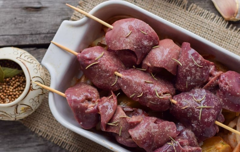 1. Этап. Печень цыплят бройлеров: Вымойте и зачистите от пленок куриную печень. Обсушите ее бумажными полотенцами. Нанизайте ее на шпажки, предварительно замоченные в холодной воде. Выложите шашлычки на лук, присыпьте розмарином, солью, перцем. Запекайте печень в духовке при температуре сто восемьдесят градусов двадцать минут.