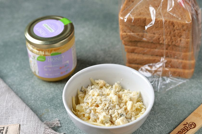 1. Этап. Сэндвичи с медом: Твердый сыр натрите на крупной терке, переложите в глубокую пиалочку, добавьте раскрошенный руками сыр с голубой плесенью. Перемешайте оба вида сыра.