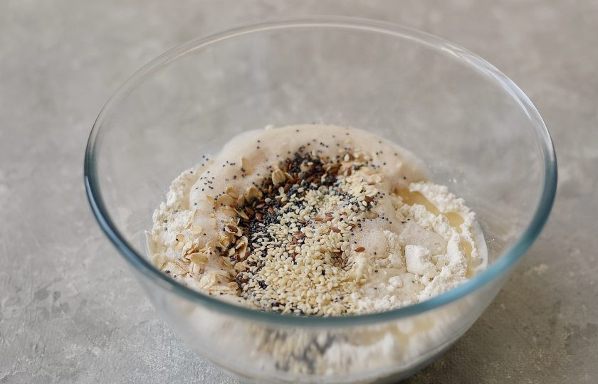 1. Этап. Злаковый хлеб в духовке: Влейте в муку дрожжи, добавьте злаки. Следом влейте растительное масло.