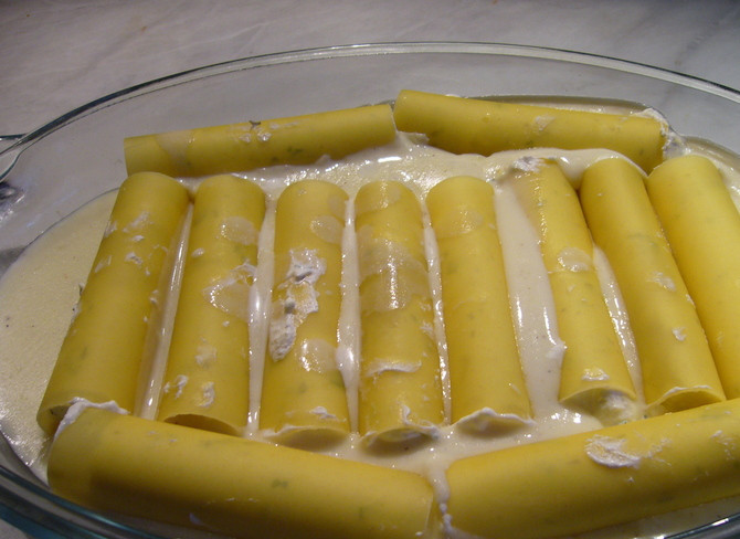 1. Этап. Каннеллони с творогом: Аккуратно фаршируем каннеллони приготовленной из творога и сыра начинкой. В форму для запекания вливаем половину соуса и выкладываем в него каннеллони.