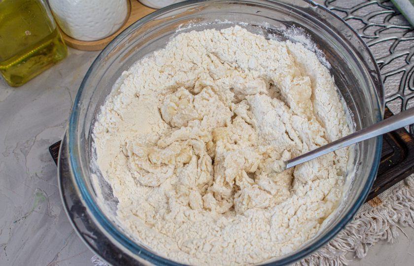 1. Этап. Чуду с черемшой: В муку влейте кипяток с маслом и интенсивно перемешайте тесто ложкой, чтобы мука заварилась. Оставьте минут на 5, чтобы тесто немного остыло.