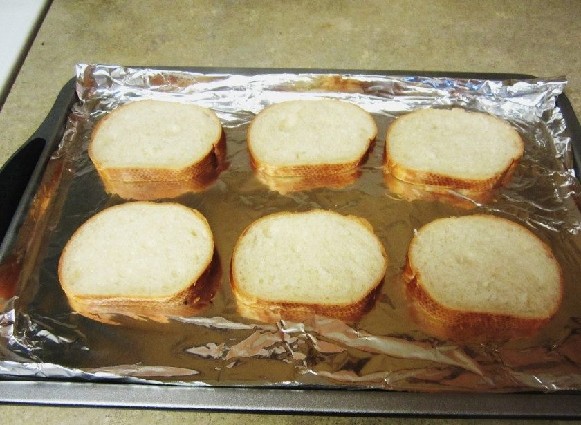 1. Этап. Бутерброды с помидорами в духовке: Разрежьте батон на несколько ломтиков, выложите на противень, покрытый пекарский бумагой или фольгой. Смажьте их оливковым маслом.